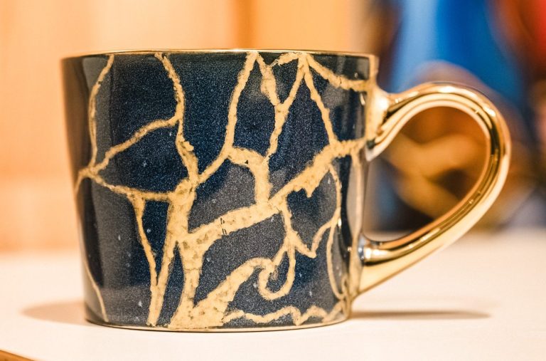 Tasse Kintsugi Une tasse noire réparée selon l'art japonais du Kintsugi.Les fissures dorées symbolisent la force,la résilience et la beauté née des épreuve